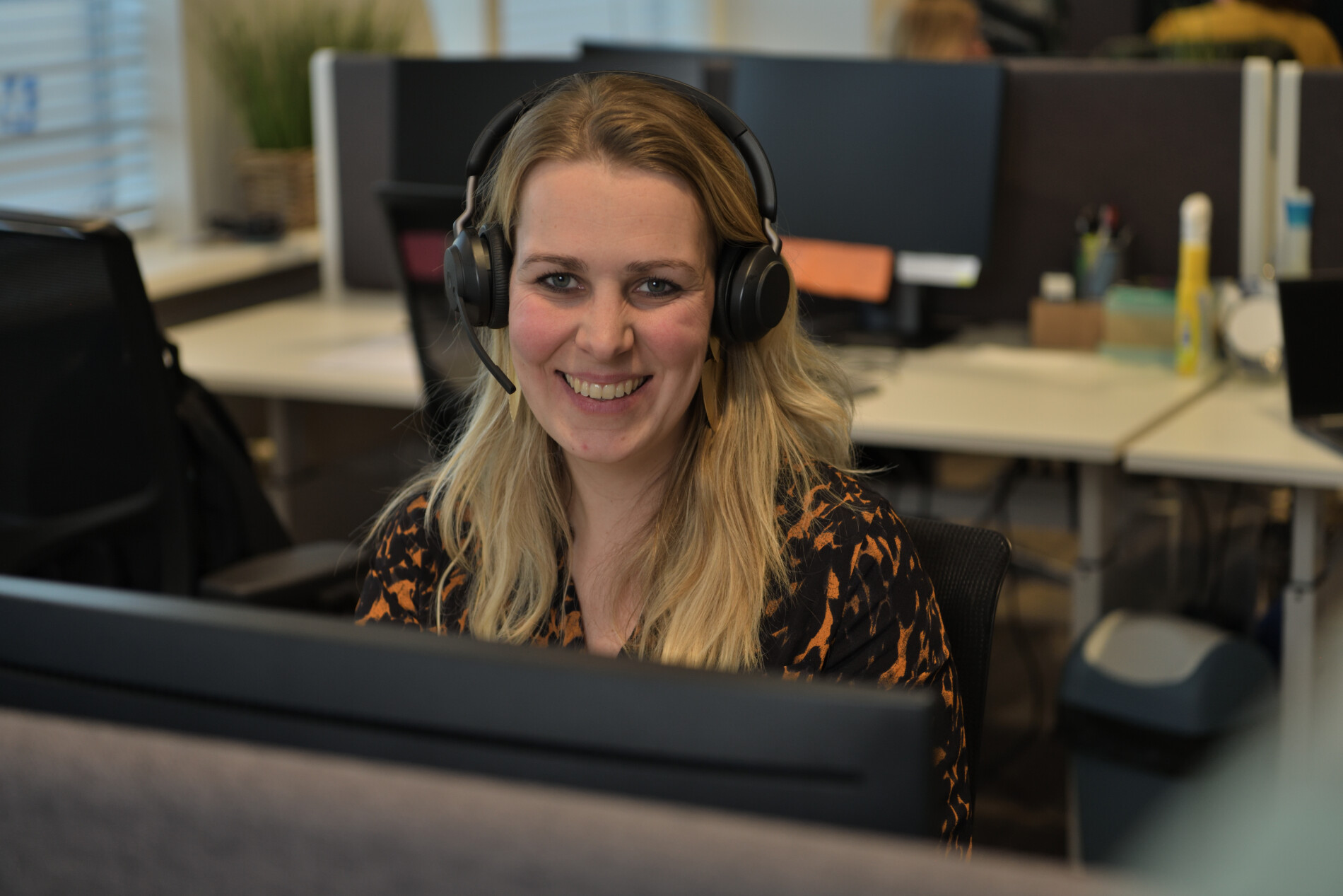 Vrouw met headset achter haar bureau