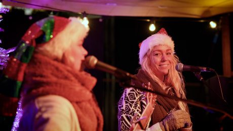 Vrouwen met een kerstmuts op het podium aan het zingen