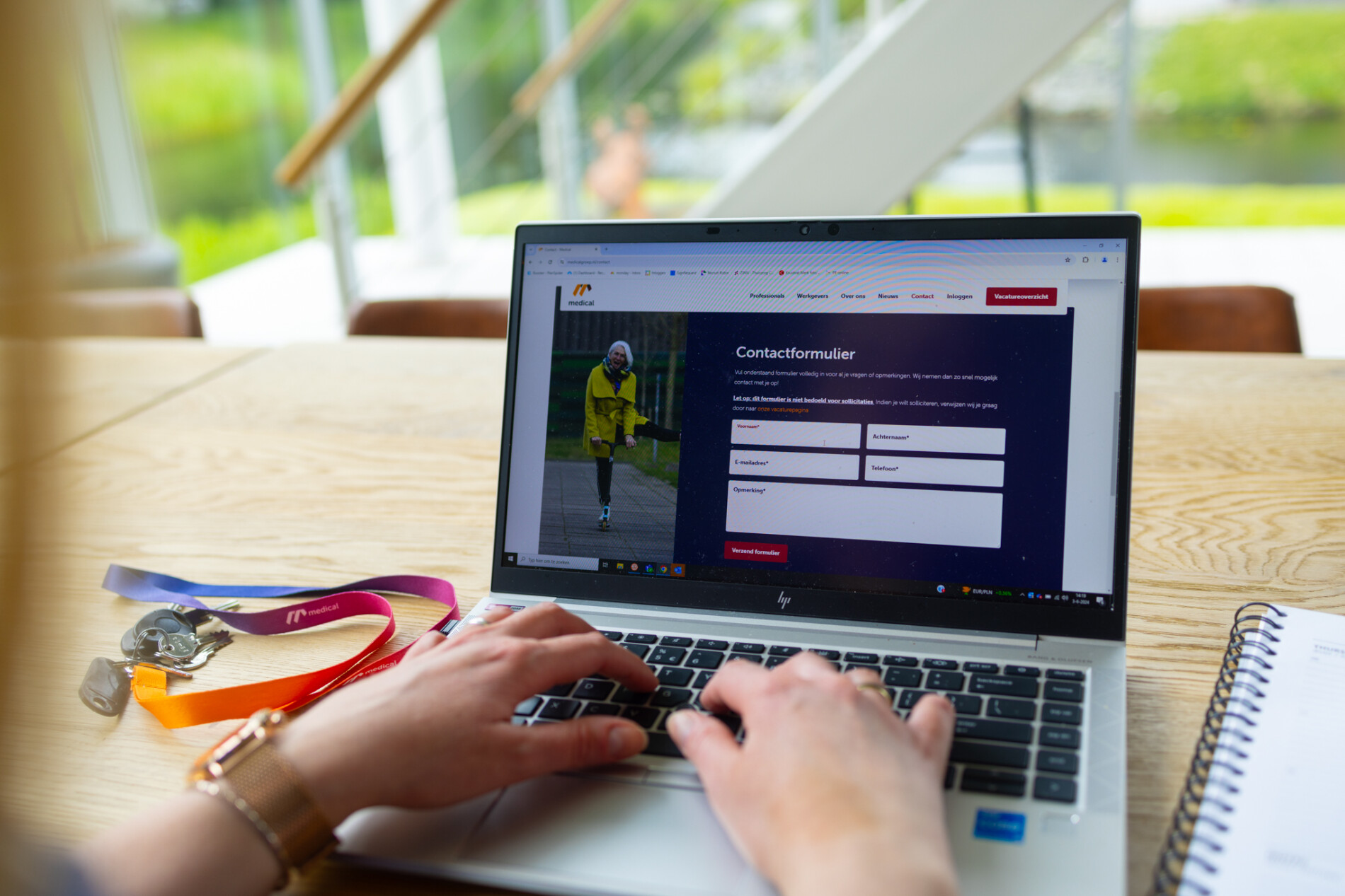 Close-up van handen die aan het typen zijn op een laptop met open scherm van Medical Groep website